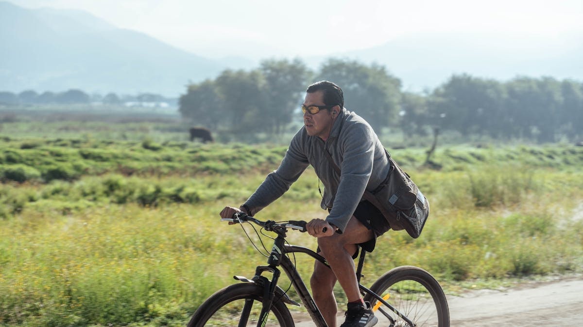 Adult man cycling on a rural path in a natural landscape, wearing casual attire.